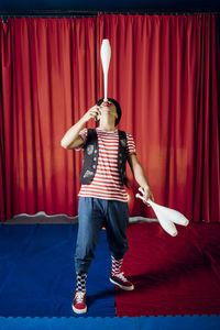 Male clown balancing juggling pin on nose in circus