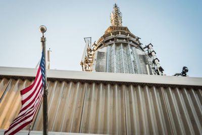 Low angle view of the usa flag on the empire state building against sky in new york 