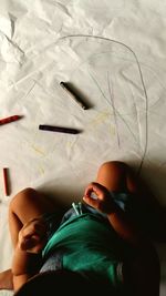 Directly above view of toddler drawing with crayons on paper