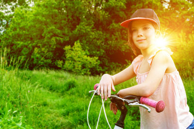 Portrait of young woman riding bicycle on field