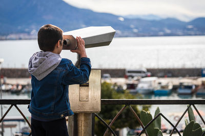 Rear view of man photographing while standing on railing