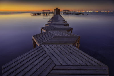 Pier over lake against sky during sunset