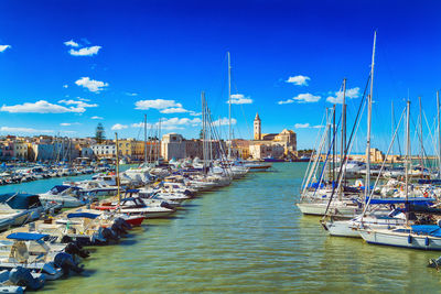 Sailboats moored at harbor against blue sky