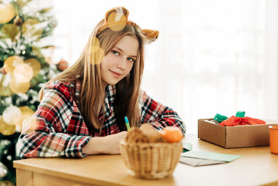 Portrait of a beautiful teenage girl writing a letter with congratulations and wishes on christmas 