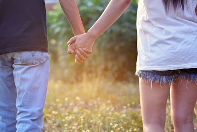 Midsection of couple holding hands