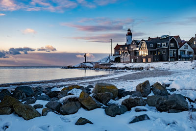 Scenic view of sea and buildings against sky during sunset