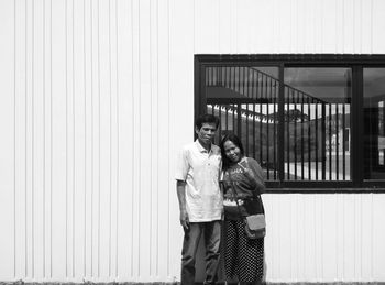 Portrait of mature couple standing against house