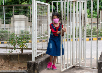 Full length view of girl with face mask at revolving gate