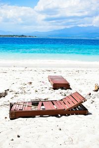 Deck chairs on beach against sky