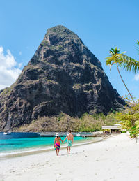 Rear view of woman walking at beach against clear sky