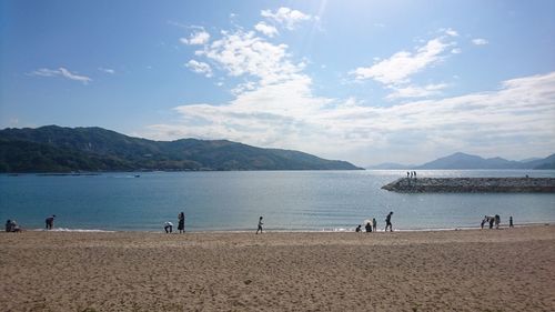 People walking at beach against sky