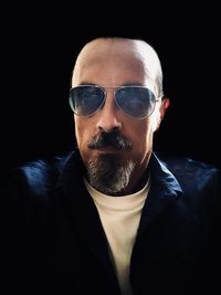 Portrait of man wearing sunglasses against black background