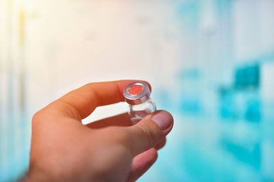 Close-up of hand holding bottle against blurred background