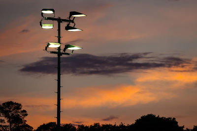 Low angle view of street lights against orange sky