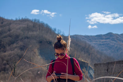 Young woman standing against mountain