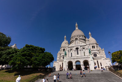 Group of people in front of building against blue sky