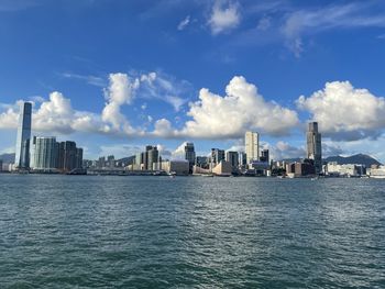 Sea by modern buildings against sky in city