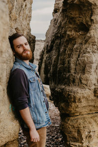 Portrait of young man leaning on rock formation