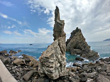 Scenic view of rocks on shore against sky