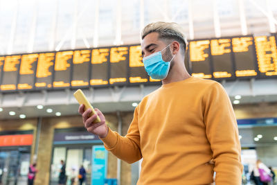 Midsection of man using mobile phone while standing in city