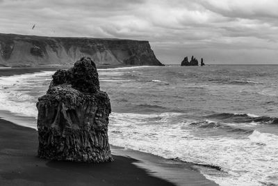 Rock formation on beach against sky