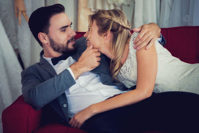 Smiling bride and groom romancing on sofa at home