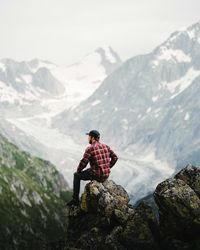 Rear view of person standing on rock against mountains