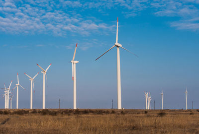 Windmills on field against sky