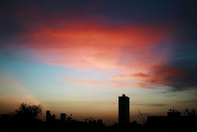 High section of silhouette buildings against dramatic sky