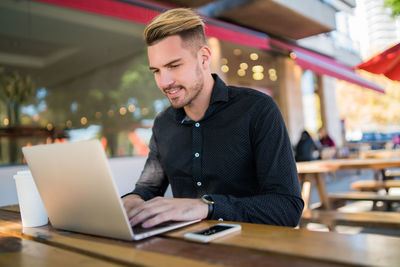 Young man using mobile phone in restaurant