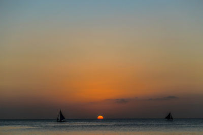 Silhouette boat sailing in sea during sunset