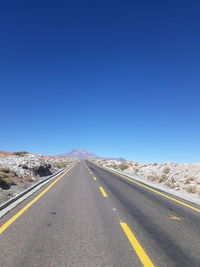 Surface level of road against clear blue sky