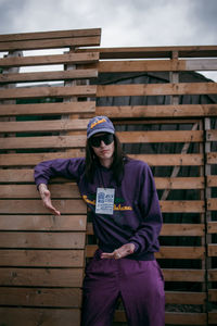 Full length of teenage boy sitting on wood