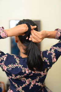 Rear view of woman tying hair