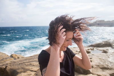 Young woman at beach against sky