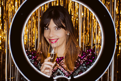 Portrait of smiling young woman with champagne against decorations
