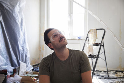 Man in protective eyeglasses renovating room at home