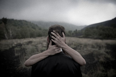 Rear view of couple kissing in field