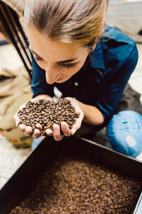 High angle view of woman smelling roasted coffee beans