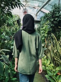 Rear view of woman standing against plants