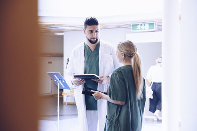 Young male doctor discussing with female nurse in hospital lobby