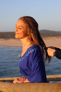 Beautiful woman looking at sea against sky during sunset