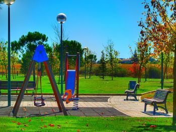 Playground in park against clear blue sky