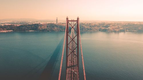 Bridge over sea against sky during sunset