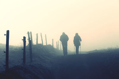 Rear view of people walking on land against clear sky