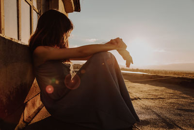 Rear view of woman sitting on land against sky