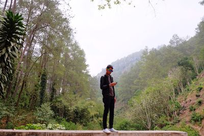Woman standing on tree trunk in forest