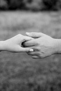 Close-up of couple holding hands against lawn