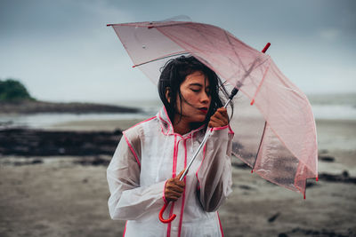 Full length of woman holding umbrella while standing on rainy day