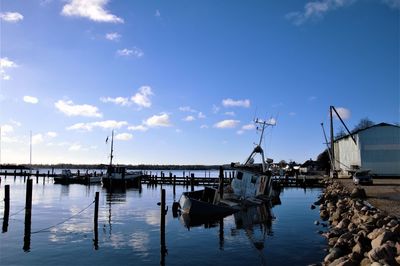 Boats moored at harbor against sky